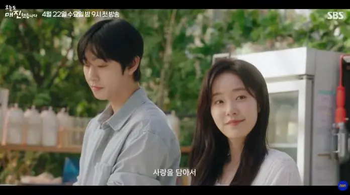 Ahn Hyo Seop stand outdoors in a bright, green setting. Behind them are shelves with glass bottles and a cooler.