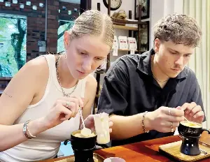 Western tourists experience Vietnamese coffee.