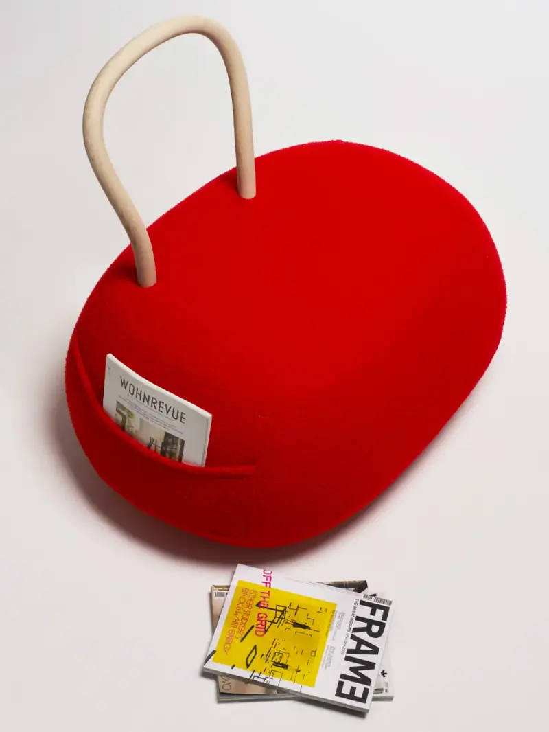 A red chair with a pocket and a looped wooden back rest from Opinion Ciatti