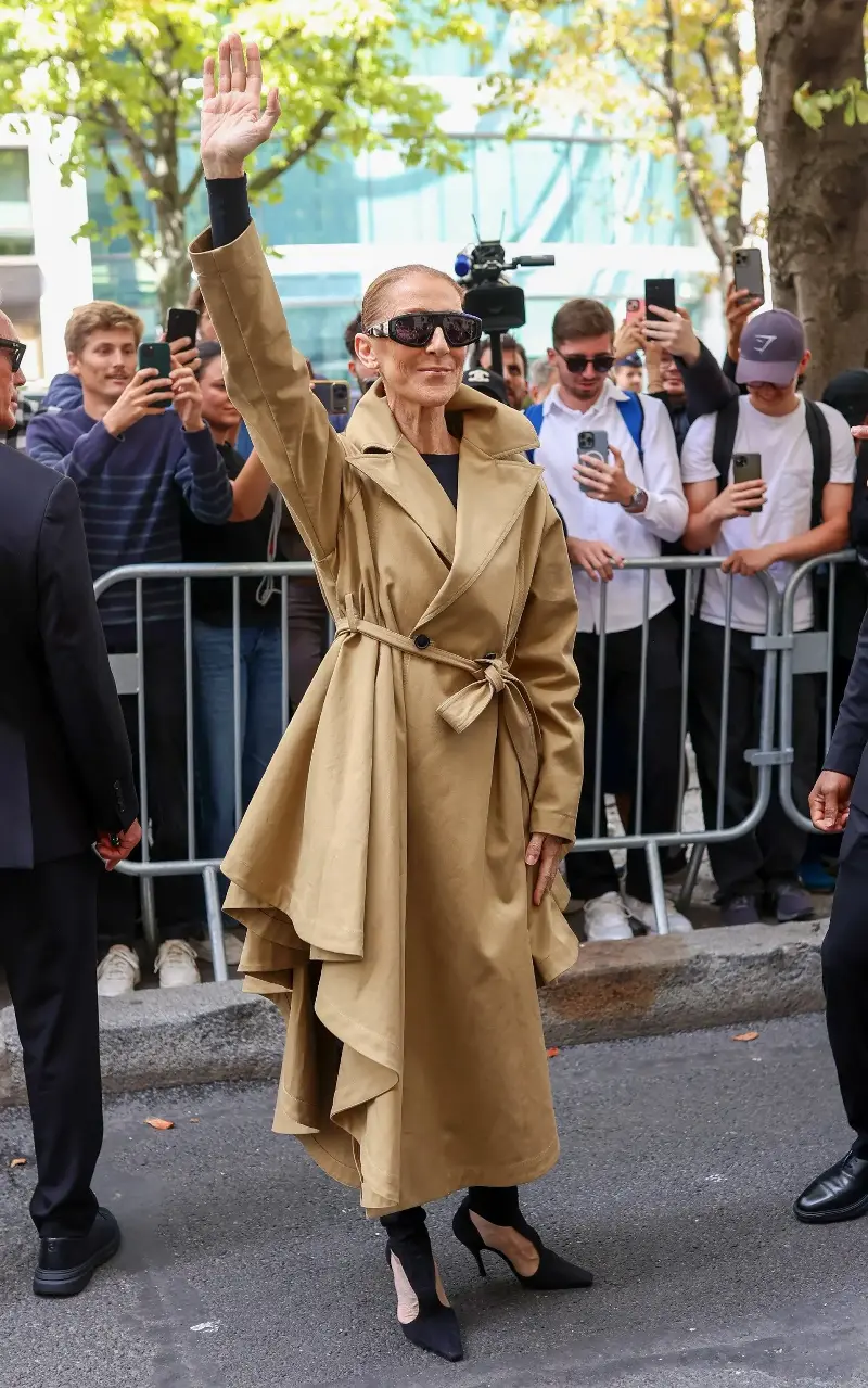 Dion wore a chic Alaïa trench coat and cut-out books to greet fans as she arrived in Paris - Marc Piasecki/GC Images