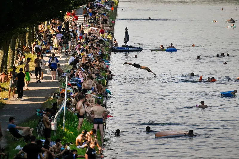 People sit at the side of a canal in Dortmund, western Germany, during a heatwave in Europe.