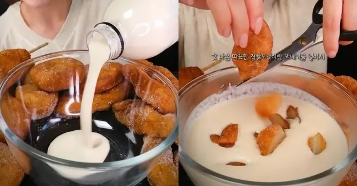 A close-up shot of a bowl filled with fried doughnuts while milk is being poured into it, with a hand cutting a doughnut with scissors.