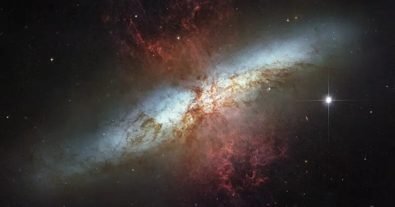 Edge-on view of the Cigar Galaxy, Messier 82, its bright disk crossed by red plumes of gas and dust