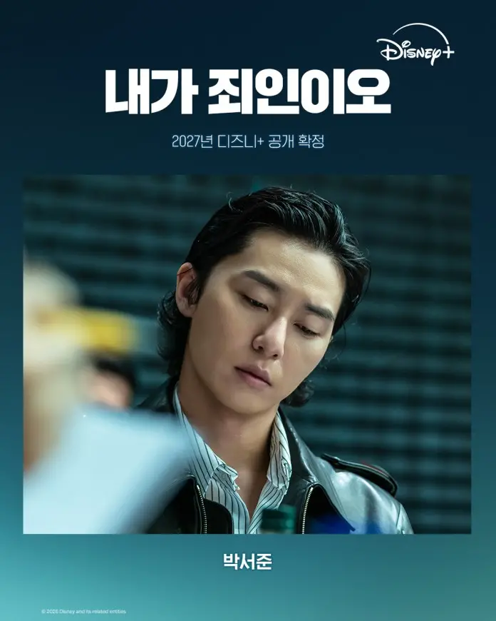 Park Seo-jun with styled black hair, wearing a black leather jacket and a striped shirt, looks thoughtfully at a document or paperwork, with a blurred background featuring a table and people, accompanied by promotional text for a Disney+ release in 2027.