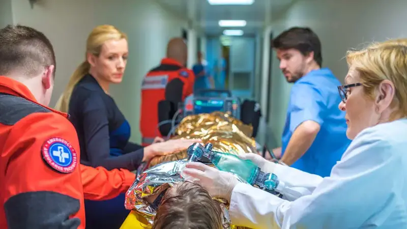 Medical staff pushing hospital gurney with a hypothermic man