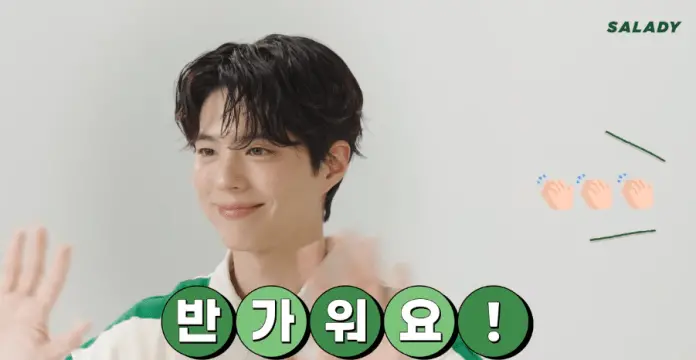 A smiling Park Bo-gum with tousled hair is waving, accompanied by playful text and clapping emojis.