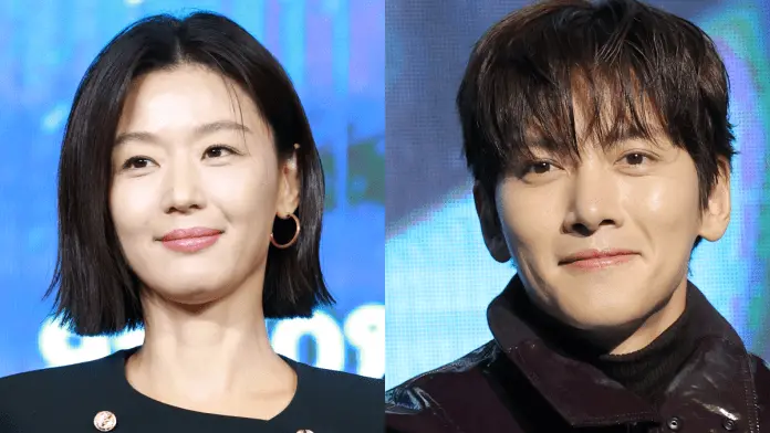 A close-up shot ofJun Ji-hyun and Ji Chang-wook , Jun Ji-hyun  with straight black hair and hoop earrings, and Ji Chang-wook with tousled hair, both smiling against a blue background.