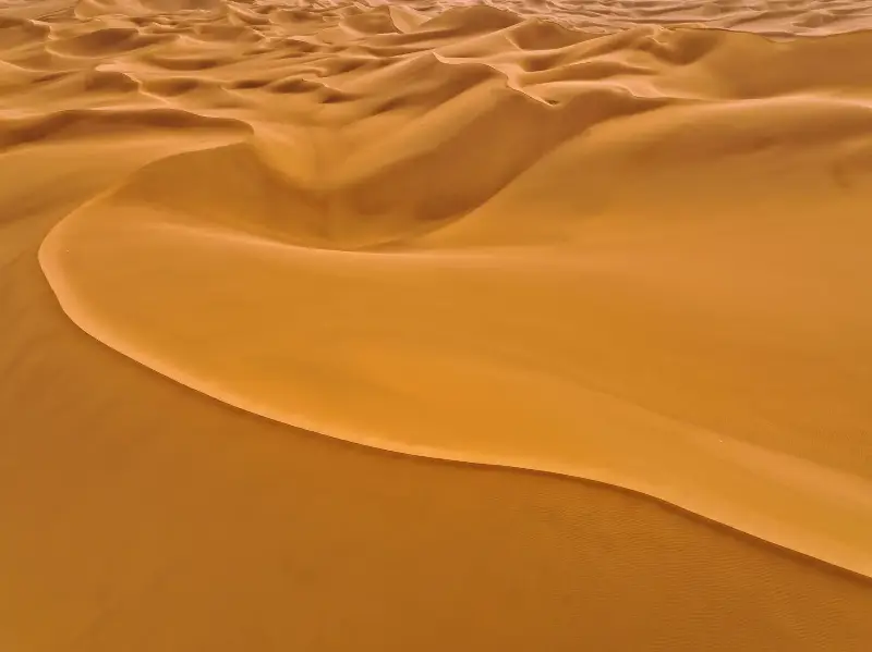 Aerial view of smooth orange sand dunes in a terrestrial desert