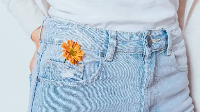 Bright orange flower in pocket blue jeans
