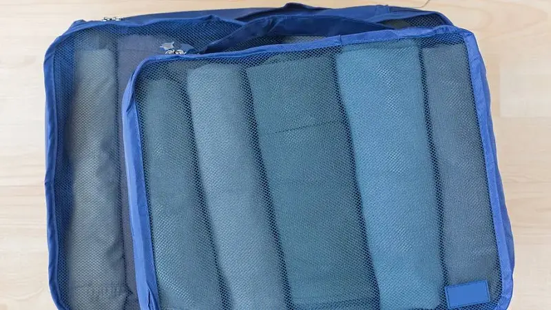 Cube meshed bags with rolled clothes. Set of travel organizer to help packing well organized