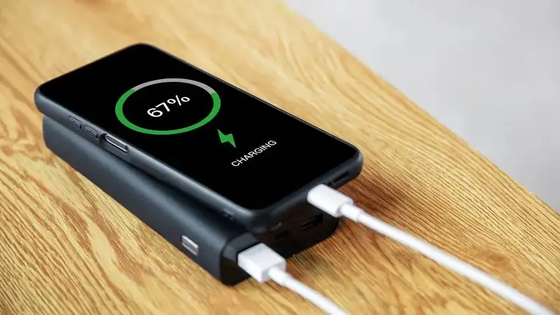 A mobile phone being charged using a power bank is on the table