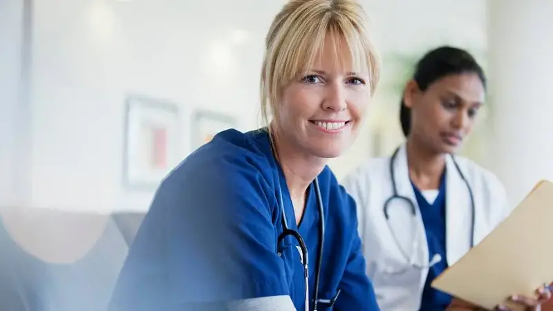 Portrait of smiling nurse sitting with doctor in hospital
