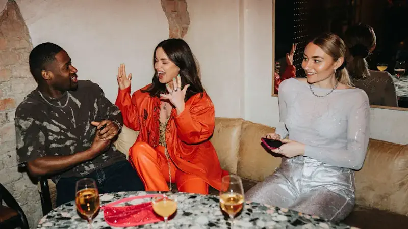 Cheerful male and female friends talking to each other while sitting on couch at nightclub