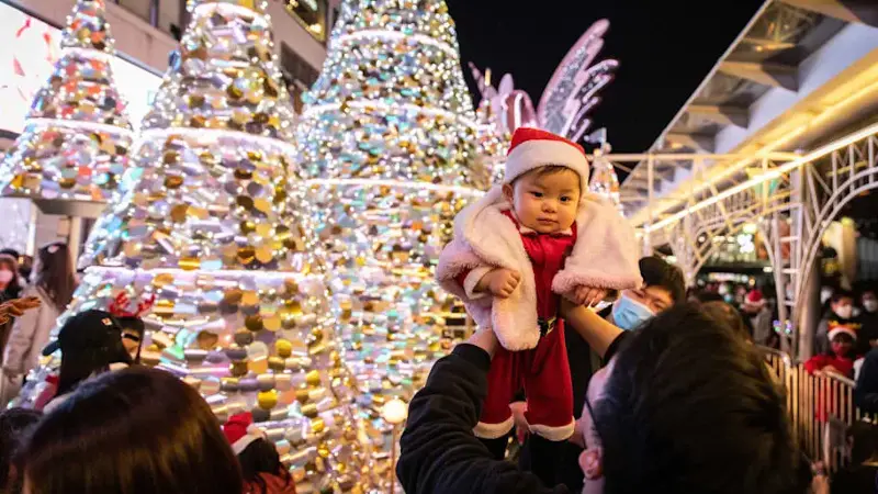 A father holds his baby son up at a shopping mall in Hong...
