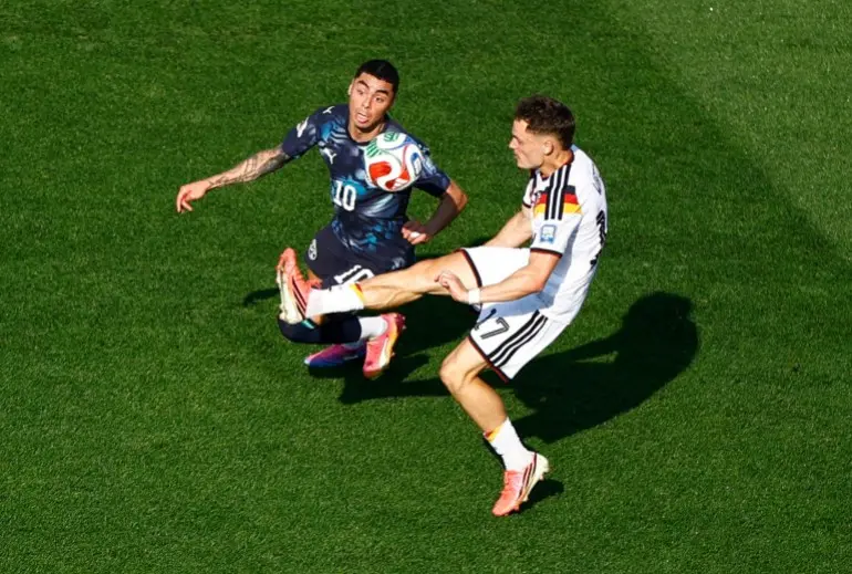 الألماني فلوريان فيرتز يصارع لاعب باراغواي ميغيل ألميرون في دور الـ32 (رويترز) 