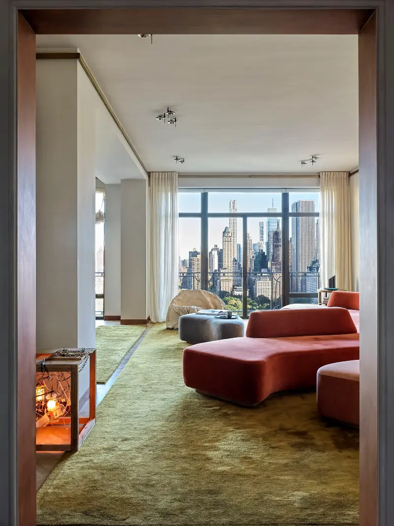 A doorway frames the apartment like a picture within a picture: the lit sculpture, the sofa, then the city.Chris Mottalini. Design: Crina Arghirescu Rogard.