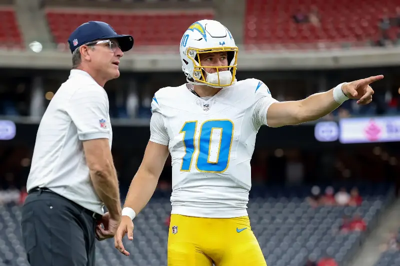 HOUSTON, TEXAS - AUGUST 13: Justin Herbert #10 of the Los Angeles Chargers talks with head coach Jim Harbaugh before a preseason game against the Houston Texans at Reliant Stadium on August 13, 2026 in Houston, Texas. (Photo by Tim Warner/Getty Images)