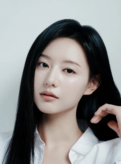 Kim Ji-won with long black hair, wearing a white shirt, gazing directly at the camera with a soft expression.