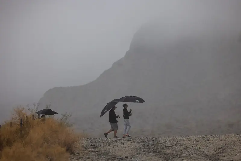 LA QUINTA, CALIFORNIA - AUGUST 20: People walk a desert hiking trail in the rain from Tropical Storm Hilary in Southern California on August 20, 2023 near La Quinta, California. More than 40 million people are under the first-ever Tropical Storm Warning issued for the area.  A warming of ocean temperatures off Mexico caused by the combination rising temperatures and of the ocean phenomenon dubbed El Niño brought about the rare weather system, according to the National Weather Service.  (Photo by David McNew/Getty Images)