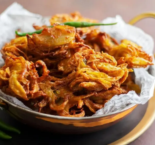 A beloved monsoon classic, Onion Bhajiya is made with thinly sliced onions coated in a spiced gram flour batter and deep-fried until crisp and golden. Best enjoyed with hot chai and green chutney on a rainy evening.