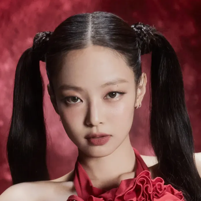 Jennie with long, sleek hair styled in two high pigtails, wearing a red ruffled top against a blurred red background.
