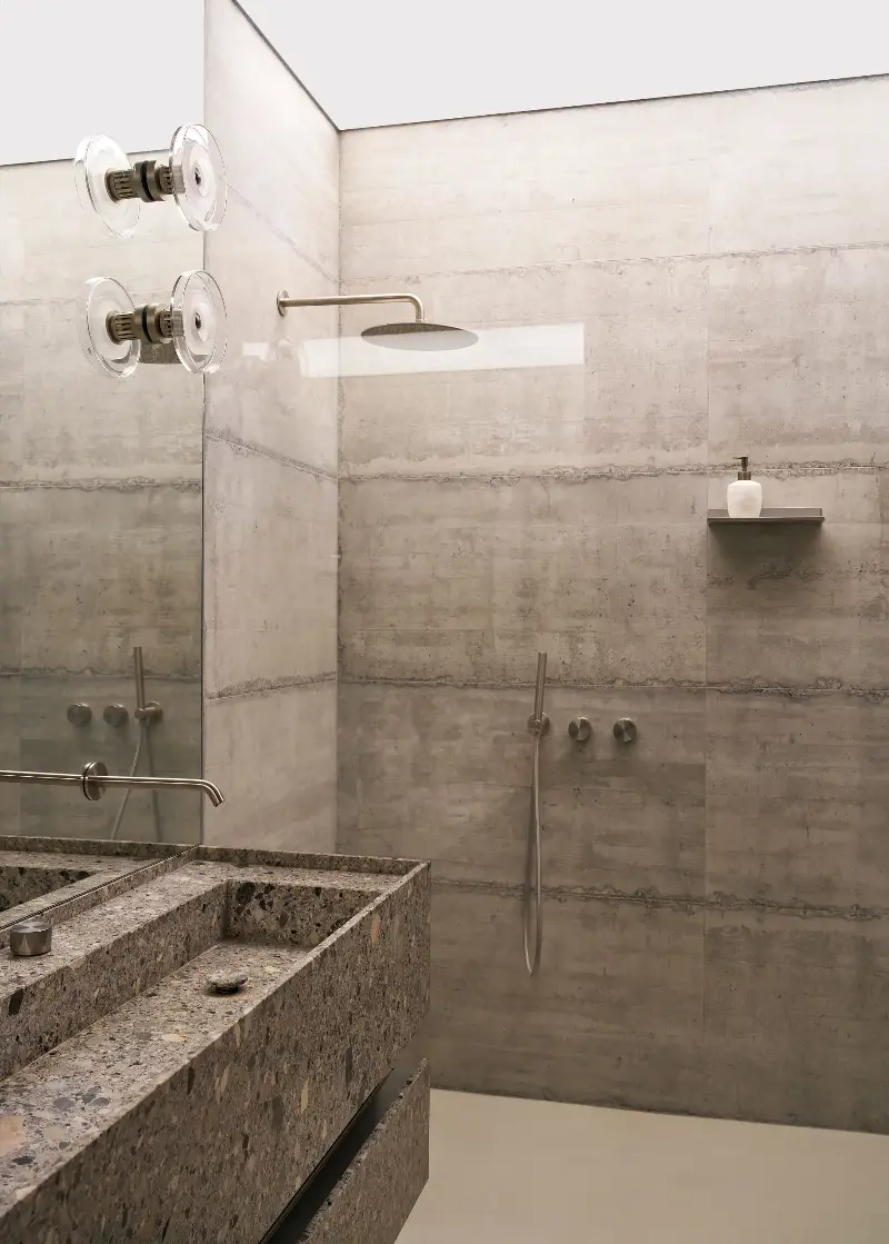 A basin in Ceppo Lombardo stone brings an organic texture that chimes with the raw concrete, while the illuminated shower ceiling pools light into this windowless area of the apartment. (Image credit: Francesco Dolfo/Living Inside. Styling: Giulia Taglialatela)