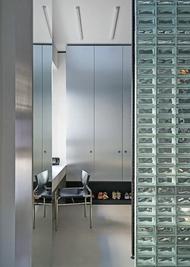 Here, industrial-edged steel and glass bricks meet the deep grain of black ash in the apartment's functional and spatial design element. (Image credit: Francesco Dolfo/Living Inside. Styling: Giulia Taglialatela)