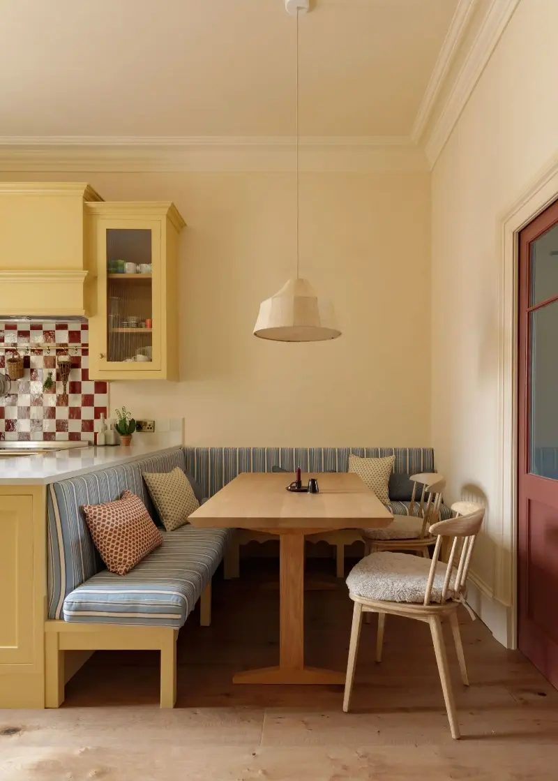 In this kitchen, Farrow & Ball's Hay adds a soft butter tone to the cabinets, alongside soft blue and burgundy.  (Image credit: Alexander Baxter. Design: Studio Mac)