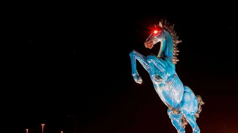 a massive blue fiberglass mustang, with glowing red eyes, standing on its hind legs