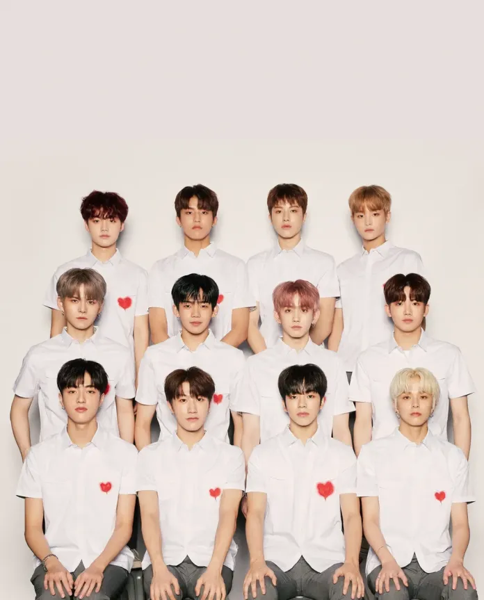 A group of twelve young men are arranged in a grid, standing in front of a plain background. They are wearing white shirts, some with red heart decorations on the left side.