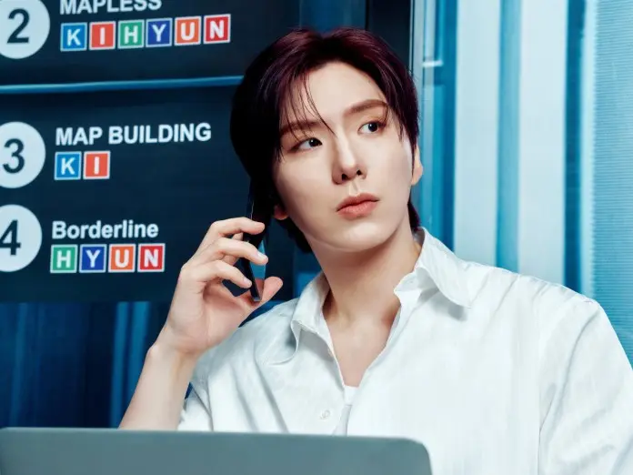 Kihyun in a white shirt sitting at a desk with a laptop, holding a phone to their ear, looking thoughtfully at a sign with different project names.