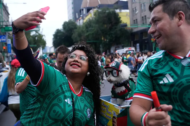 A fan, left, takes a photo with a dog named Osito, wearing a Mexico national soccer team jersey, next to Jorge Rangel before the World Cup Group A soccer match against South Korea in Mexico City, Thursday, June 18, 2026. (AP Photo/Marco Ugarte)
