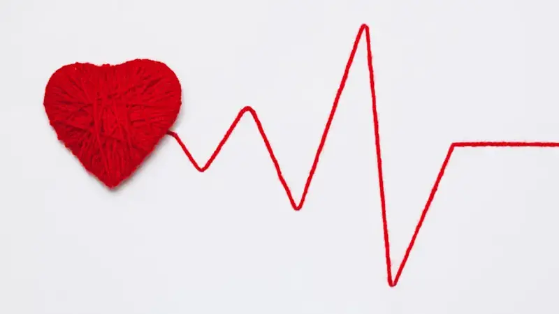 red yarn heart with thread like ECG pattern