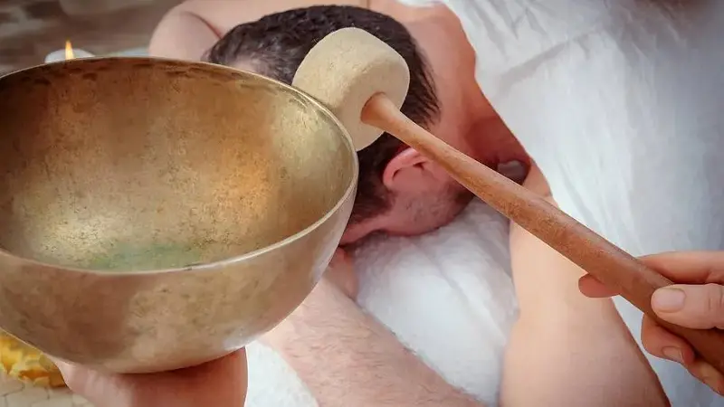 sound bath singing bowl near man's ear