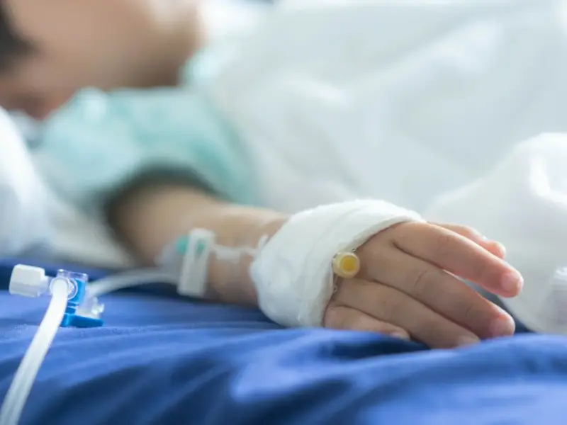A child in a hospital bed with intravenous drip.