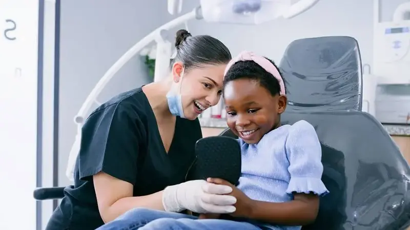 Healthcare, dentist or girl child with mirror for consulting, dental procedure and oral hygiene or happy at hospital. Dentistry, patient or kid with orthodontist for pediatric, gum disease or checkup