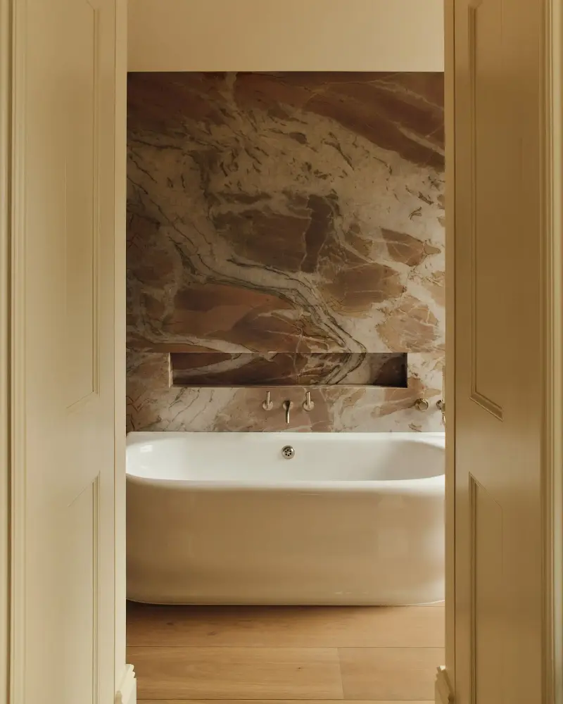 A stunning freestanding bath sits at the center of this guest bathroom with walls covered in pink and green Splendido quartzite.Studio Hahn. Design: Gangar