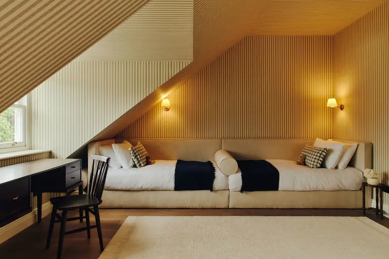 Attic bedroom, styled for children featuring bespoke twin bed and bolster upholstered in GP & J Baker fabric (Image credit: Studio Hahn. Design:Gangar)