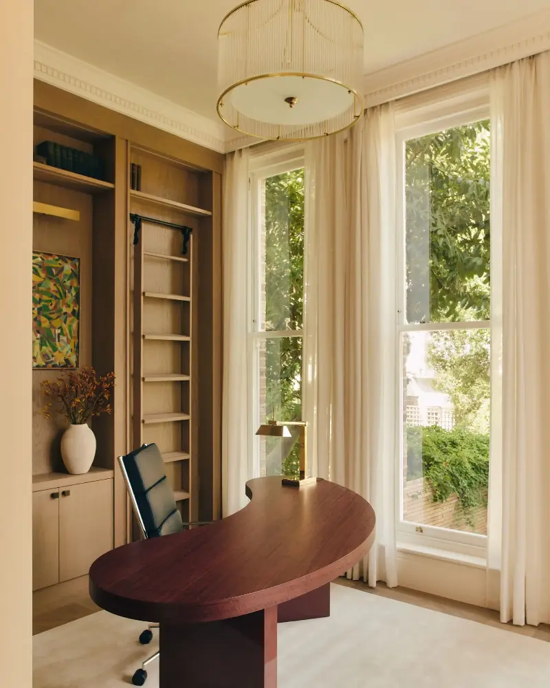 The study, with a bespoke almond desk and Eames Executive leather chair on a cream rug, enjoys views of the garden. (Image credit: Studio Hahn. Design: Gangar)