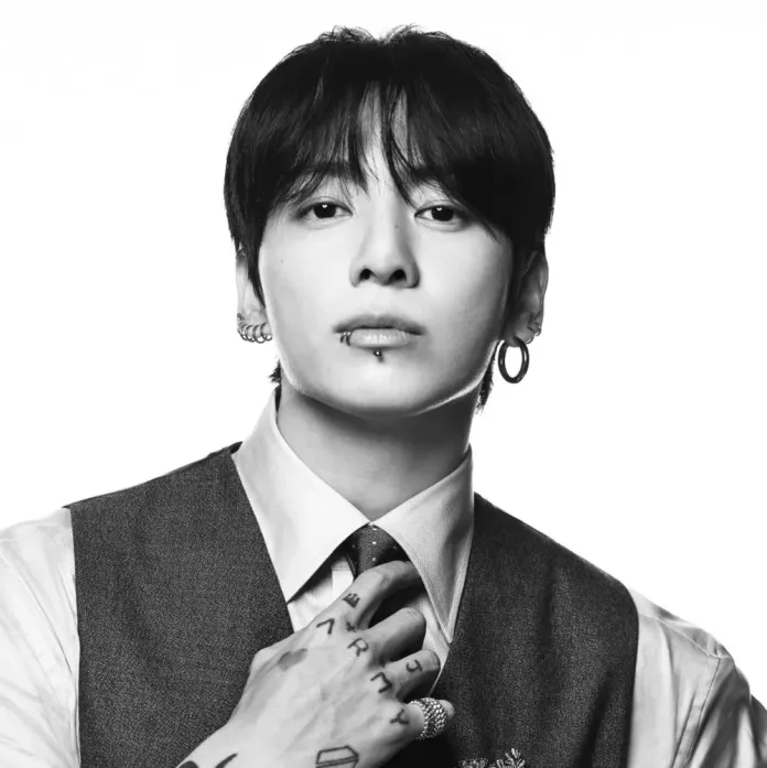 Jungkook with dark hair and earrings is gazing directly at the camera, wearing a formal outfit with a vest and tie. The image is in black and white, capturing a confident expression.