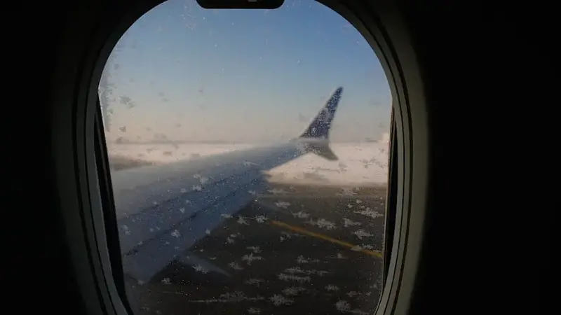 Airplane window covered in snowflakes