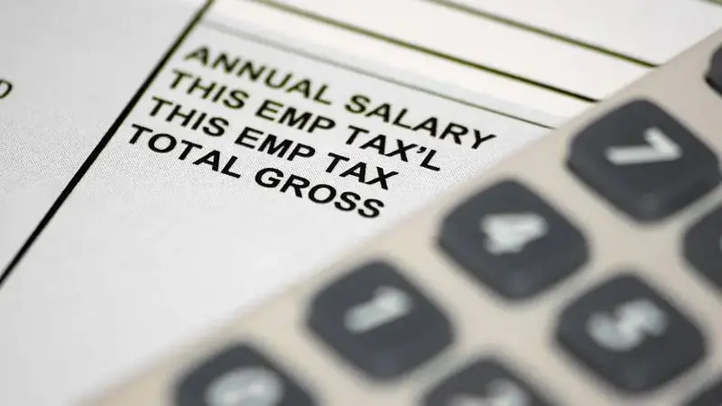 A pay slip underneath an out of focus calculator