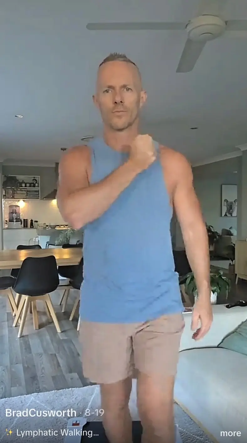 One TikTok user taps his chest while lymphatic walking on a walking pad. Swinging the arms is supposed to help fluid move through tissue that filters out harmful cells and other substances (@bradcusworth/TikTok)