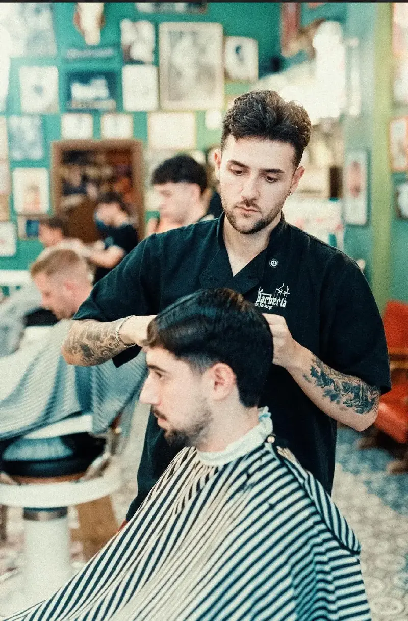 Un peluquero cortándole el pelo a uno de sus clientes