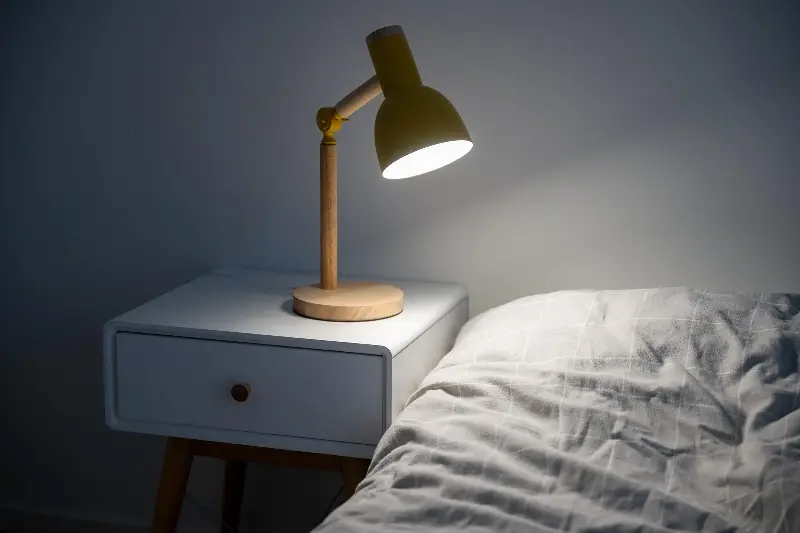 Cozy bedroom nightstand with modern desk lamp and soft bedding