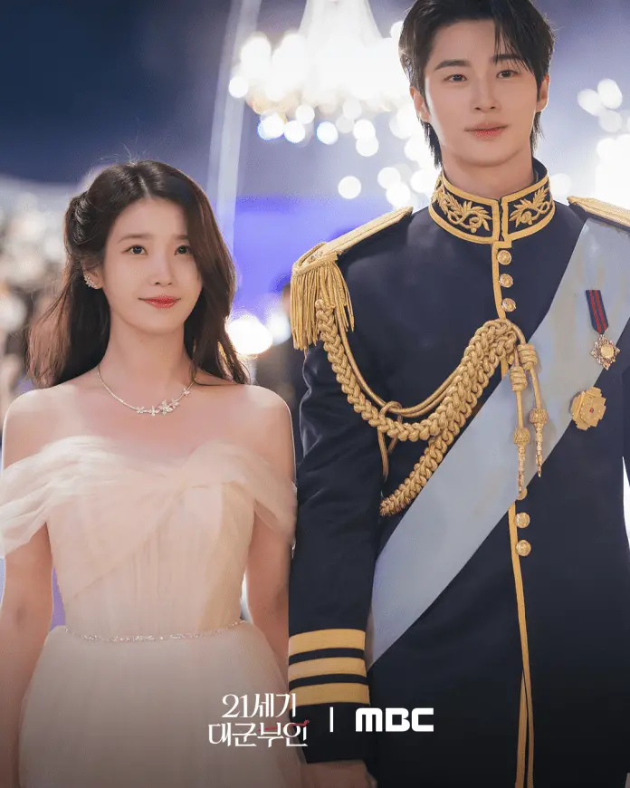IU and Byeon Woo-seok in a flowing off-shoulder gown and a man in a royal military uniform walk together, surrounded by a glamorous event ambiance.