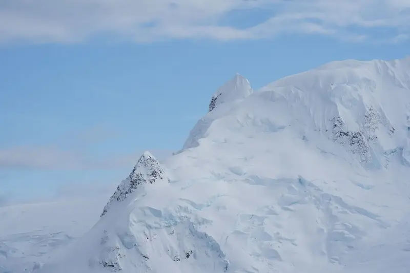 Stunning snow-covered mountains under clear blue Antarctic skies, showcasing nature's icy beauty.
