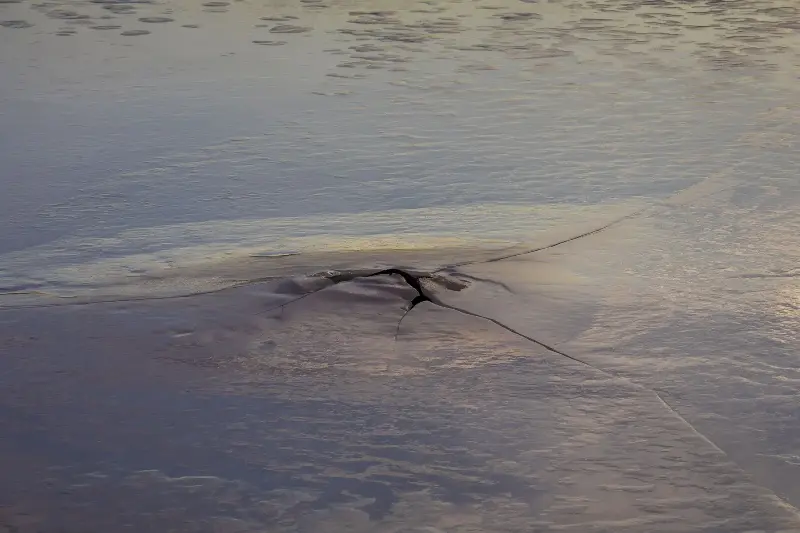 Abstract cracked ice reflecting sunset colors, showcasing nature's beauty.