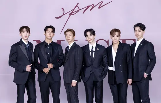 Ok Taecyeon dressed in stylish black and white suits, standing in a line against a light pink background with the text '2PM' and 'MUSICAL' displayed prominently.