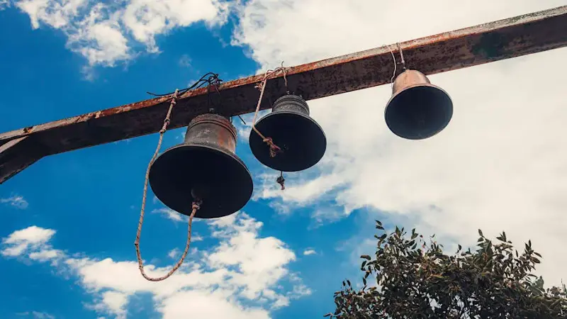 Three old church bells against sky